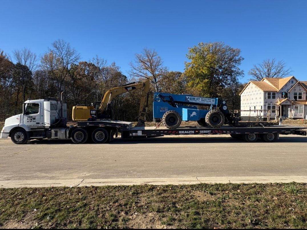 CAT excavator and boom lift loaded at subdivision
